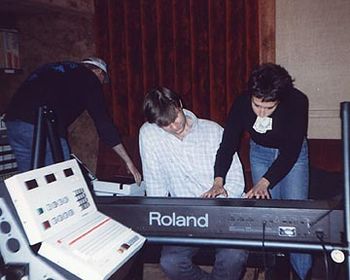 Carolyne showing Joe Terry a piano part.  With her hands busy, she puts money for a food delivery in her mouth!
